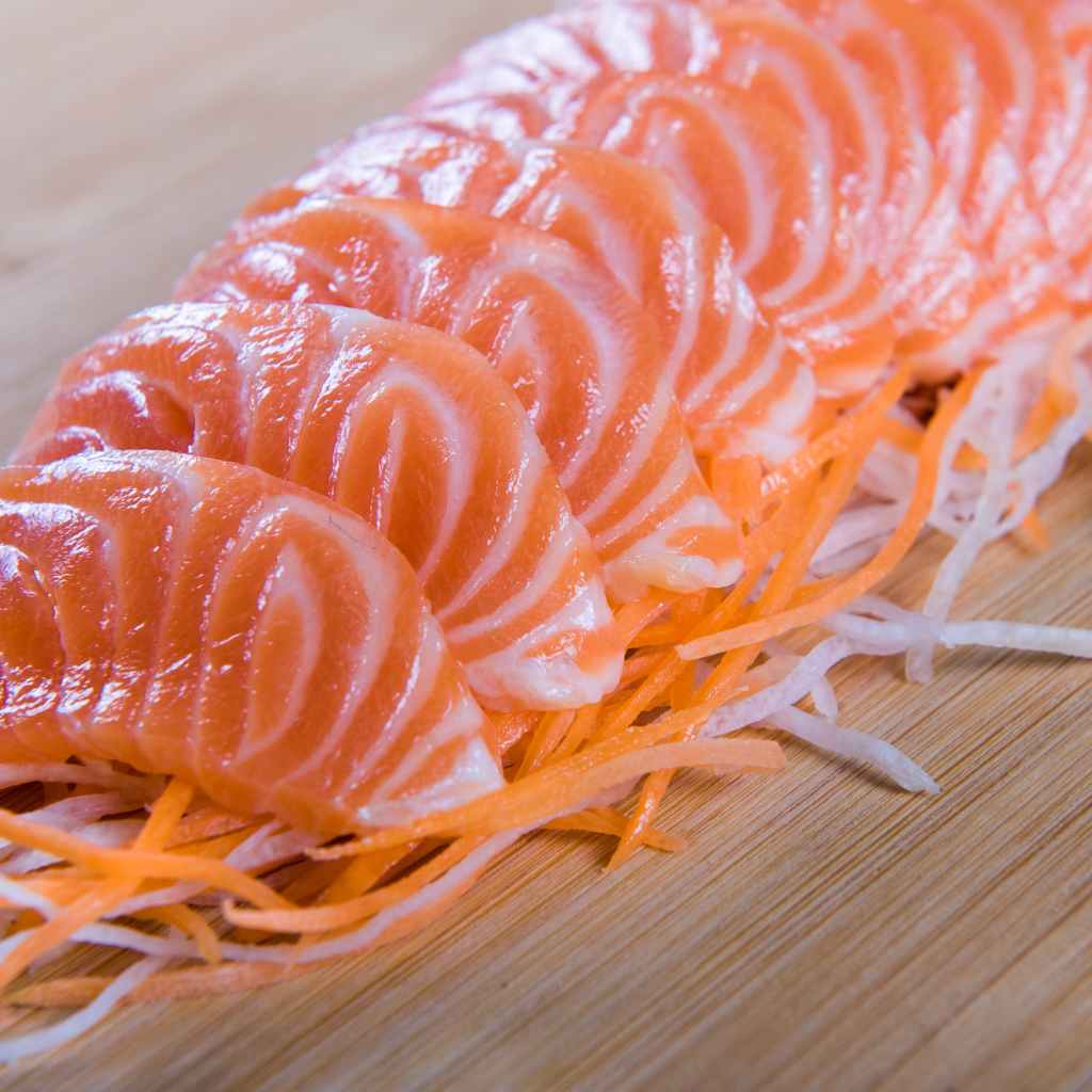 Sashimi de Salmão fatiado em cima de legumes